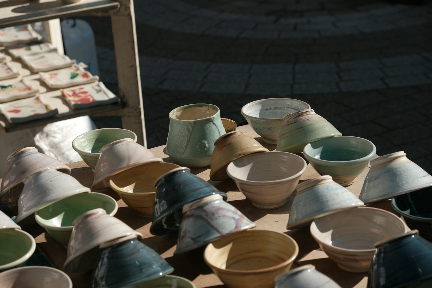 Handmade ceramic bowls and cups arranged on a wooden surface.